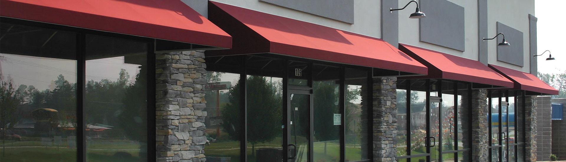 Red awnings over storefront windows with stone columns