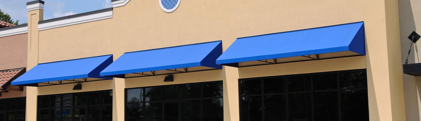 Blue awnings over large storefront windows on a tan building