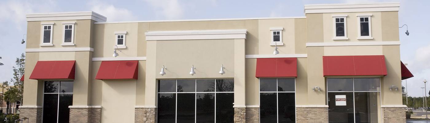 Red awnings above windows on a tan commercial building