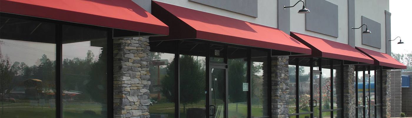 Red awnings over storefront windows with stone columns