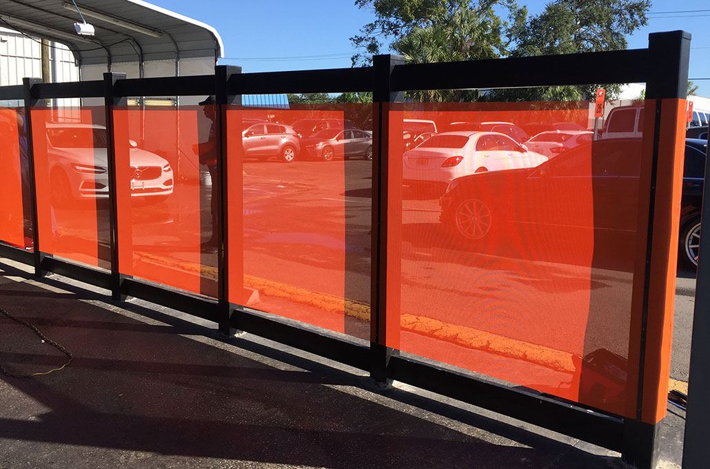 Black steel frame with orange mesh screen panels around a parking area